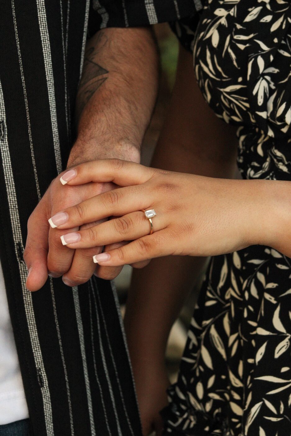 Close detail of engagement ring, hands clasped