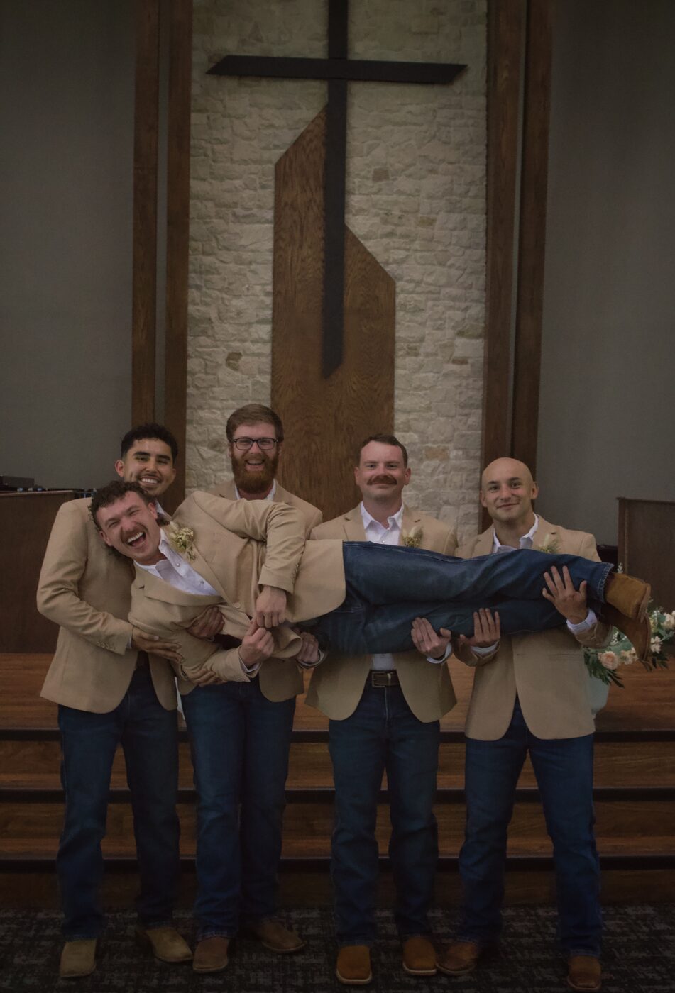 Groomsmen carrying the groom, laughing